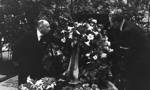 Степан Бандера поправляє квіти на могилі Євгена Коновальця.